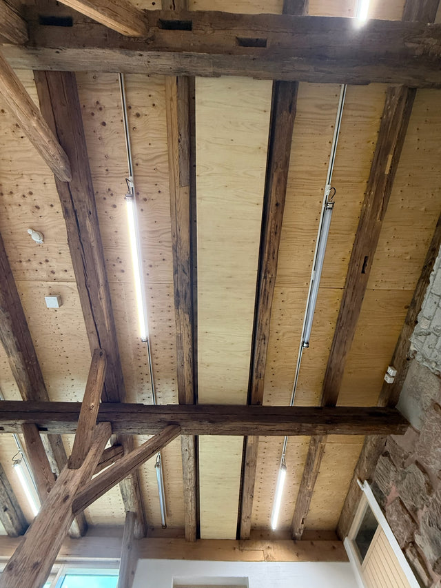Custom-made acoustic elements between historic wooden beams on a ceiling